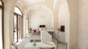 Un interior espacioso con techo abovedado, un área de comedor con mesa y sillas, una cocina con mostrador y electrodomésticos, y un televisor en la pared.