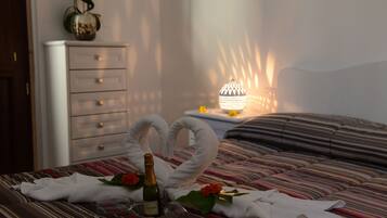 Ein Bett mit gestreifter Bettwäsche, eine Champagnerflasche und zwei zu Schwänen geformte Handtücher.
