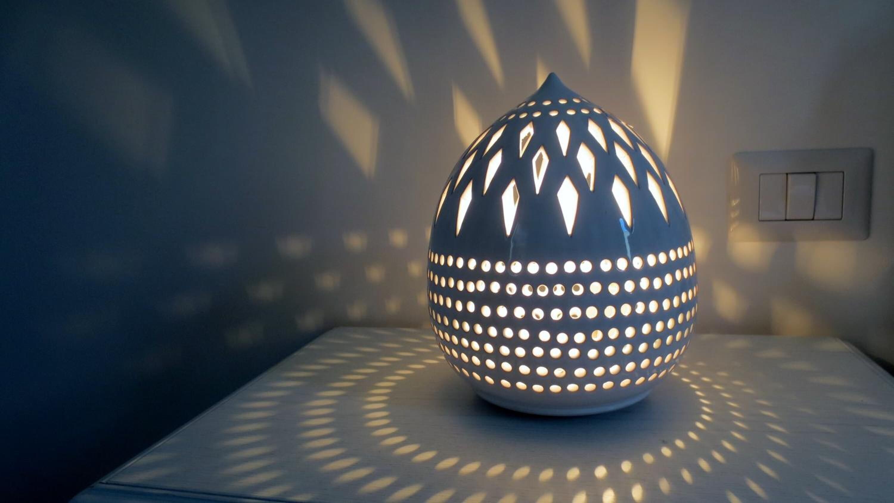 Una lampada sferica con un motivo geometrico, che proietta un'ombra circolare su una superficie piana.