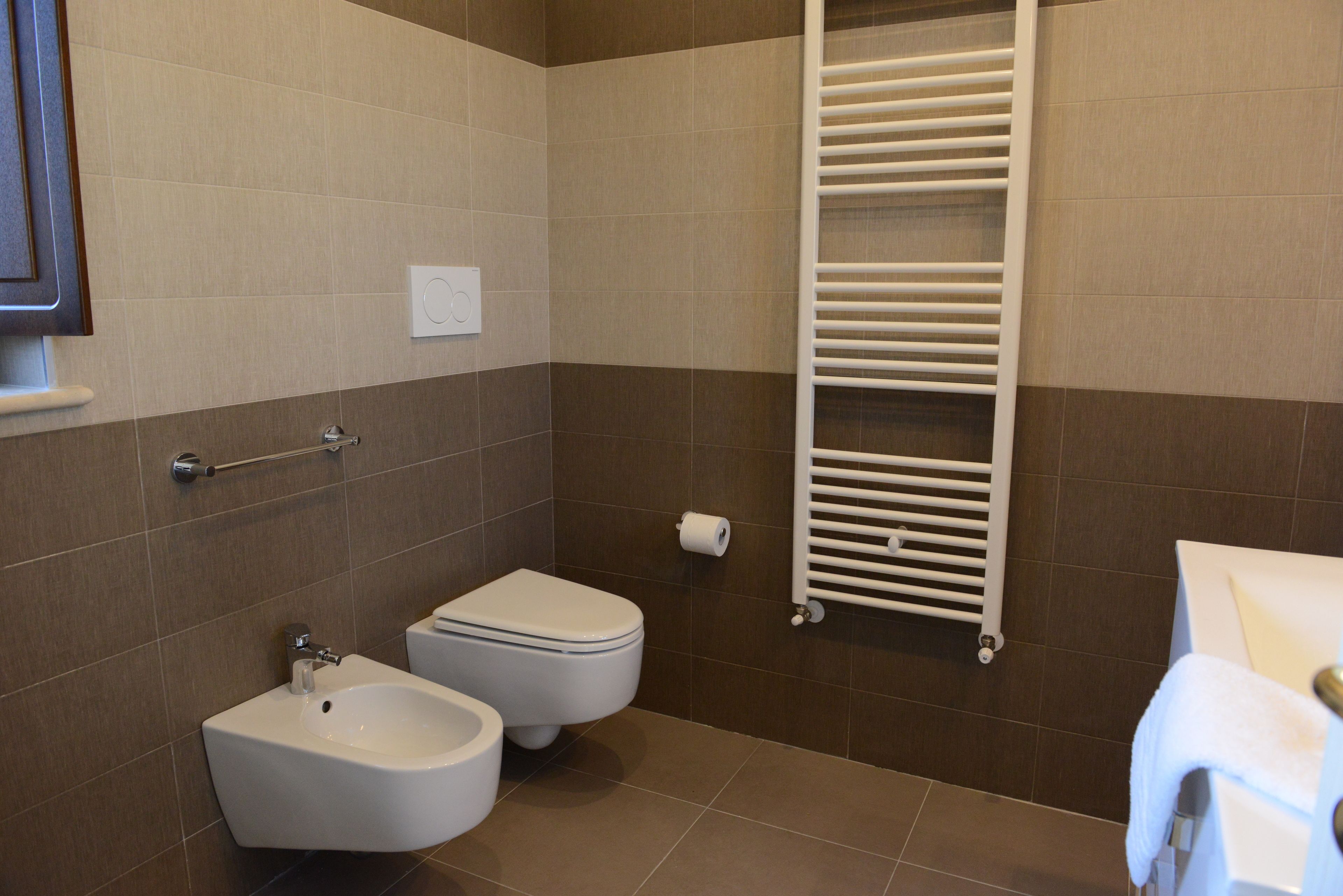 A modern bathroom with a bidet, toilet, and towel rack.