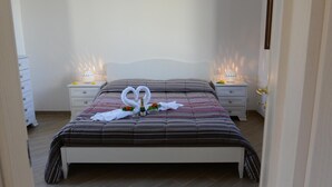 Una cama bien hecha con una colcha a rayas, dos lámparas de noche y una botella de champán.