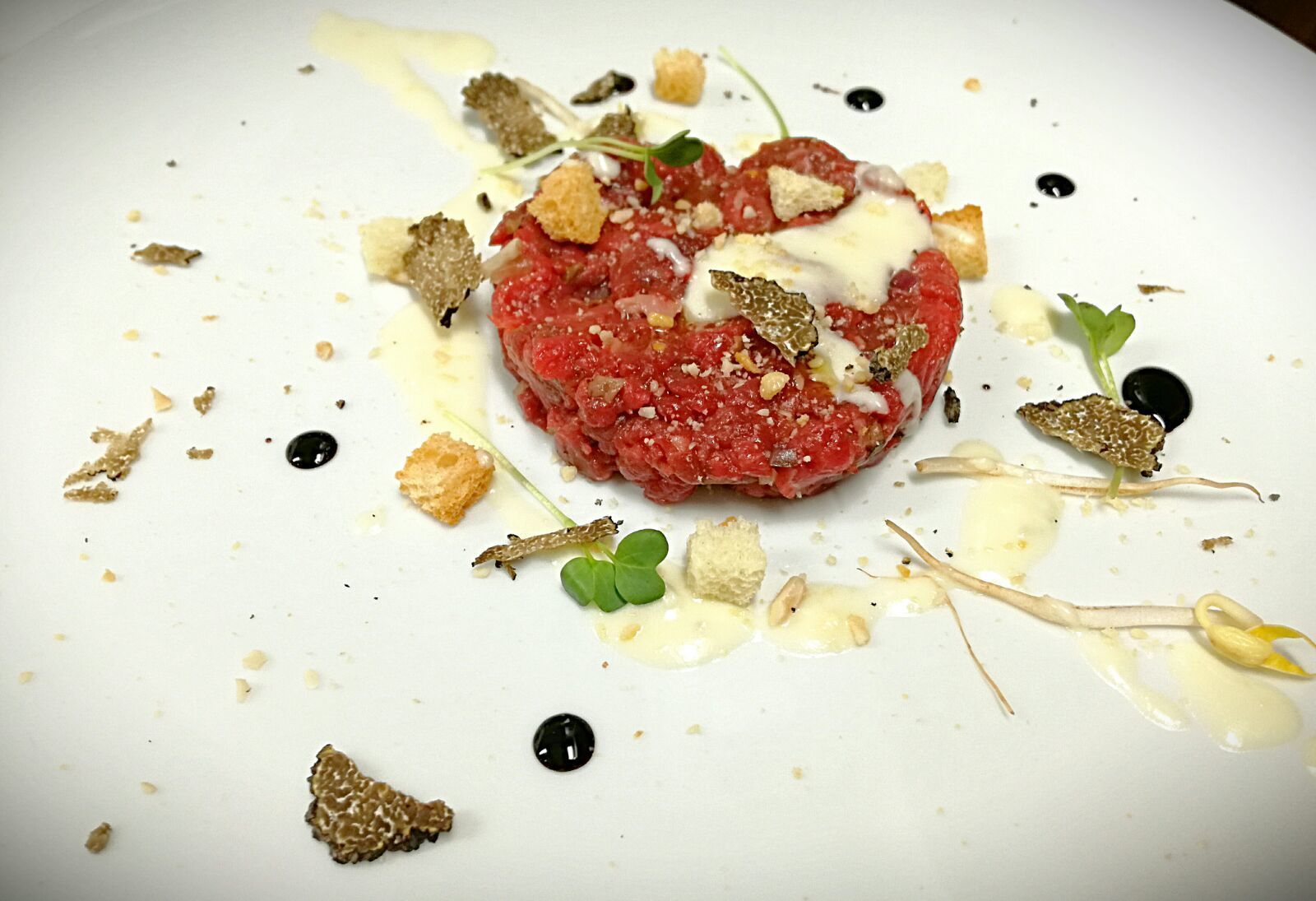 Un plat composé d’une galette de viande centrale, agrémentée de diverses garnitures et sauces.
