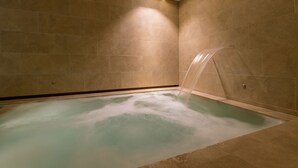 A modern bathroom with a large bathtub, tiled walls, and a built-in shower. - Borgo Cadonega Relais & SPA (Viano)