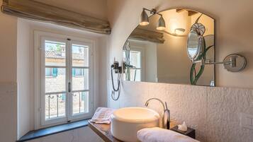 A bathroom with a large window, a round sink, a mirror, and a towel rack.