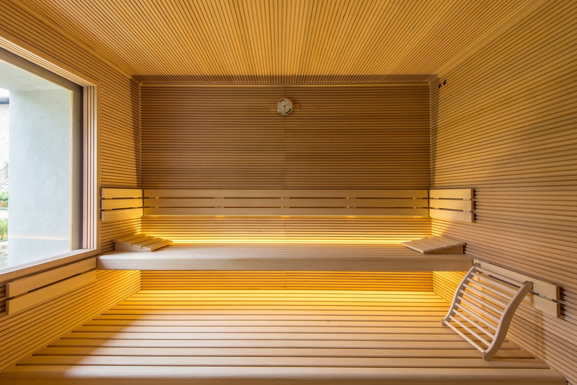 Eine moderne Sauna mit Holzlamellen, einer Sitzbank und einer Wanduhr.