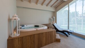 A spa area with a wooden bench, a hot tub, and two lanterns. - Borgo Cadonega Relais & SPA (Viano)