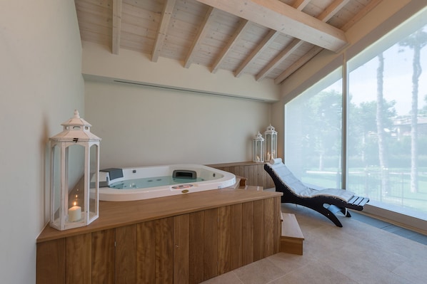 A spa area with a wooden bench, a hot tub, and two lanterns. - Borgo Cadonega Relais & SPA (Viano)