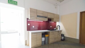 A modern kitchen with light wood cabinets, a red backsplash, and a built-in oven. - One Lucky Hostel - Old Town (Wroclaw)