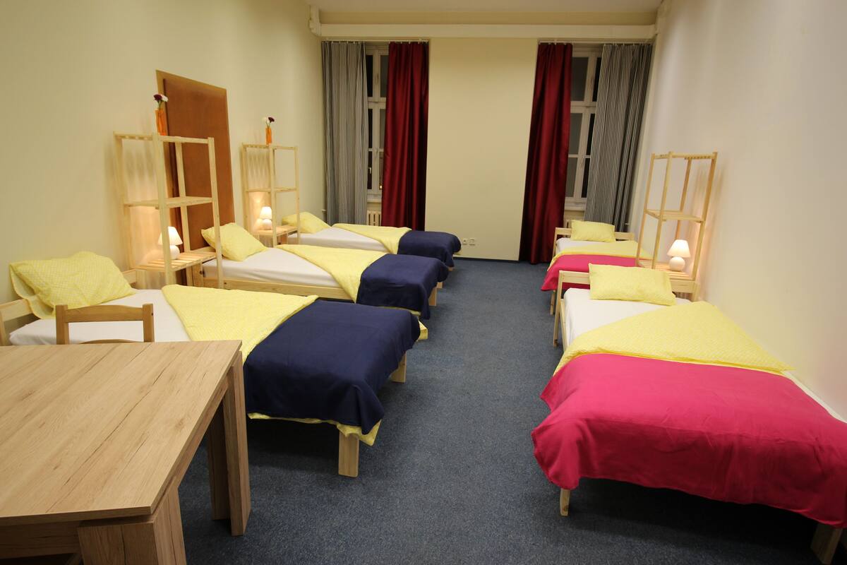 Una habitación de hotel con cuatro camas individuales, una mesa de madera y un escritorio.