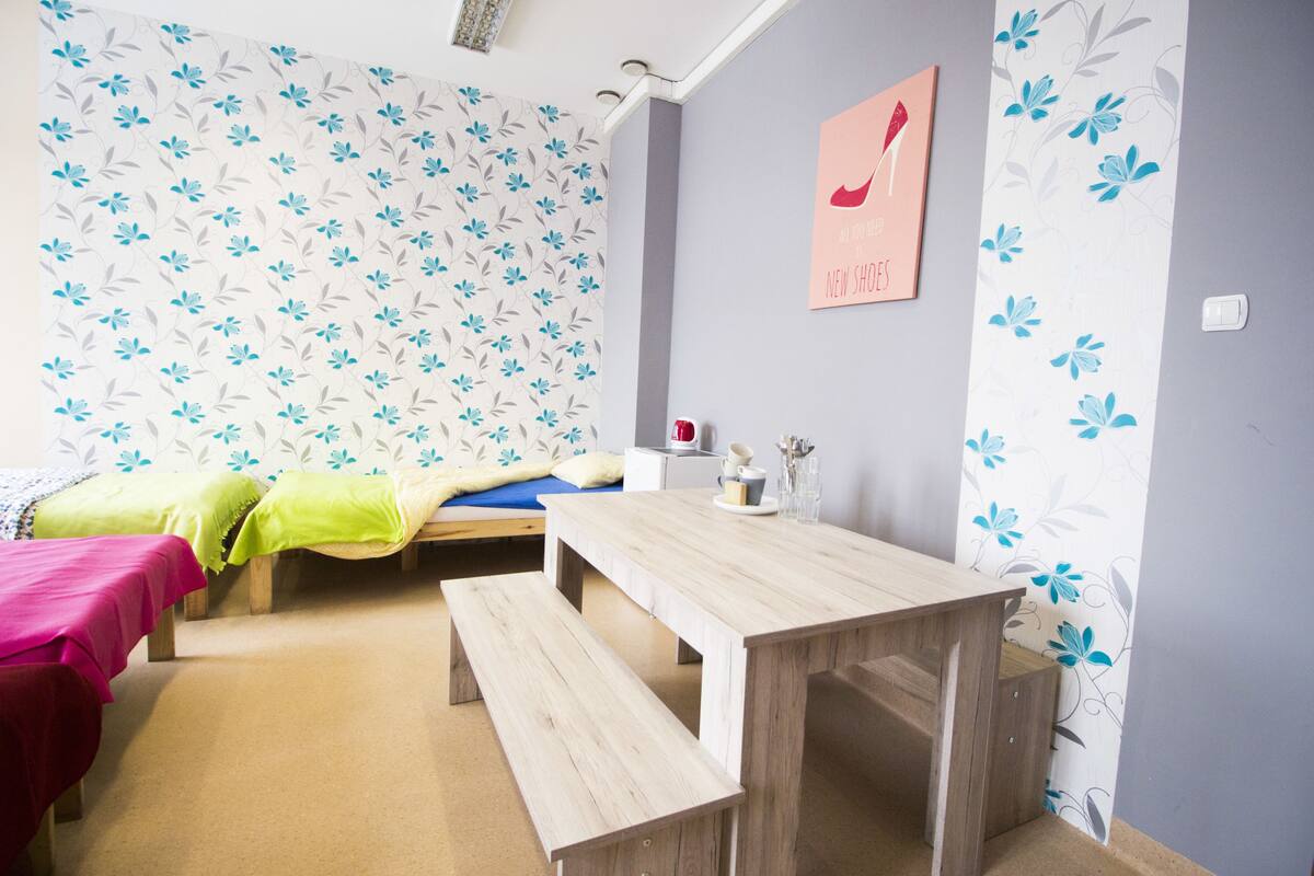 Una habitación con dos camas, una mesa de madera y un banco.
