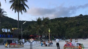 Un evento en la playa con escenario, asientos y palmeras.