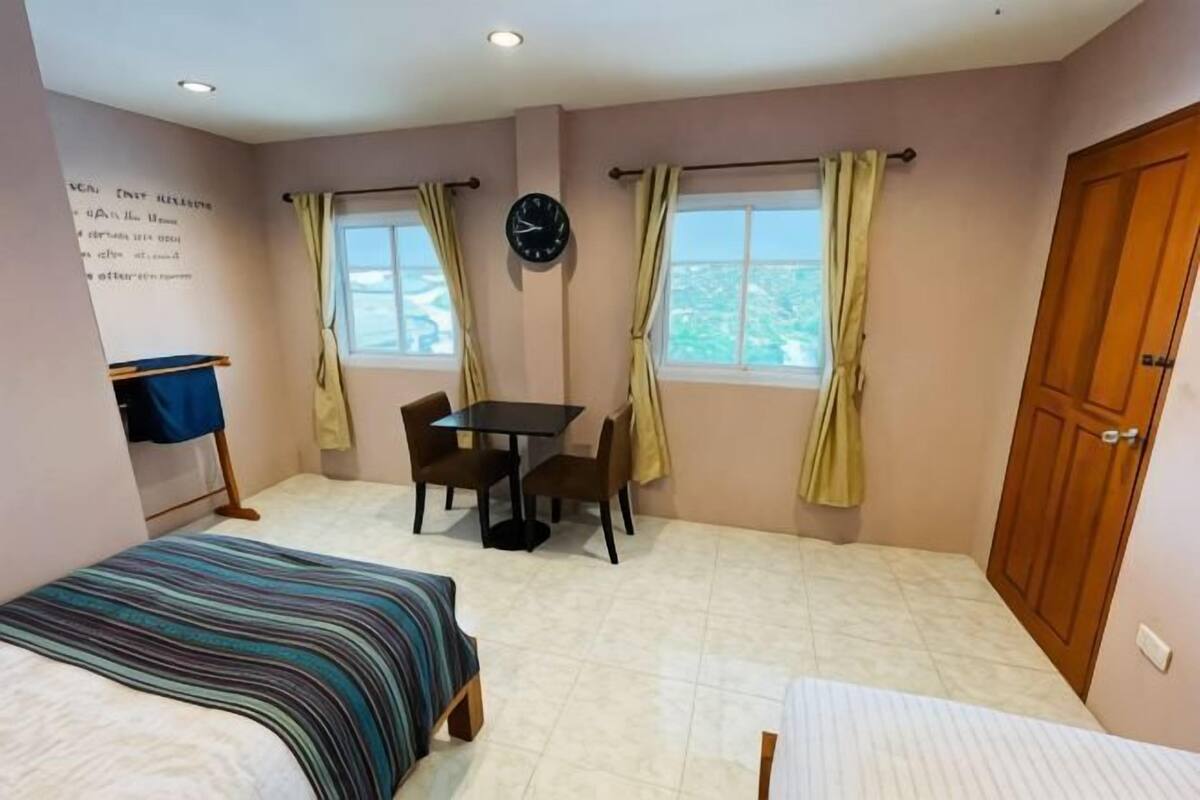Een slaapkamer met een bed, een tafel, twee stoelen, een klok en een kledingkast.