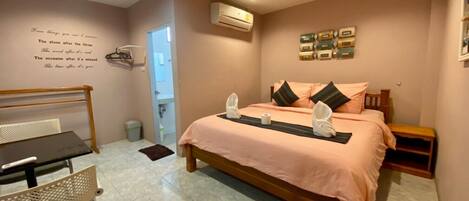 Un dormitorio ordenado con cama, mesita de noche, silla y una pared con una cita.