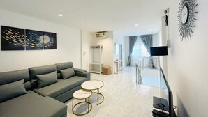 Una sala moderna con un sofá gris, dos mesitas redondas y obras de arte en la pared.