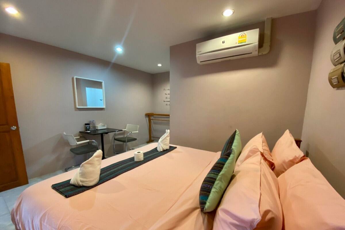 Hotelkamer met een bed, bureau, stoel, airconditioning en een spiegel aan de muur.
