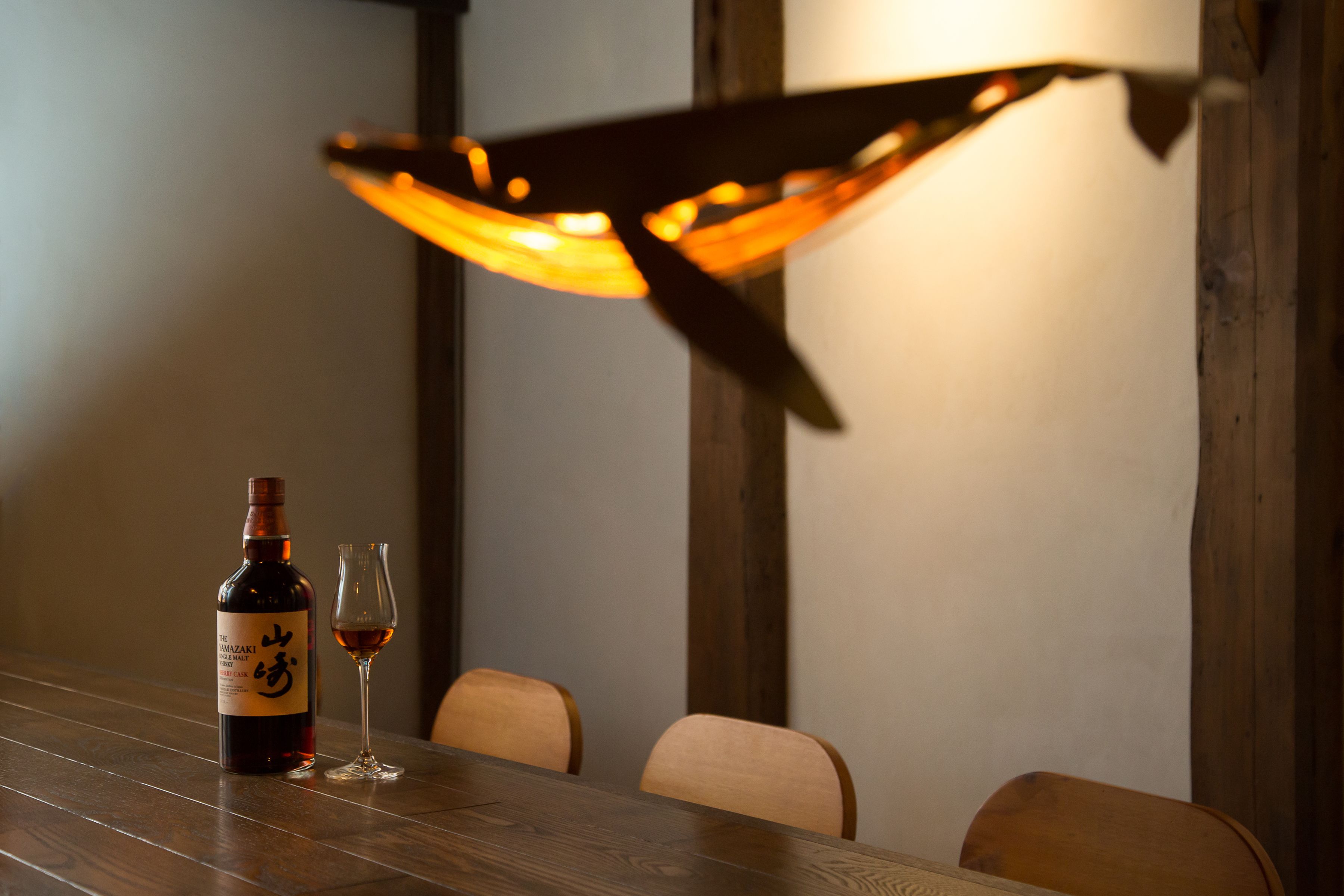 A wooden table with a bottle of wine and a glass on it.