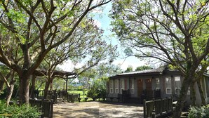 A wooden deck with benches, a small building with a tiled roof, and trees surrounding the area. - FangShug B&B (Fenglin)