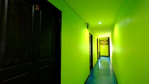 A hallway with green walls and a blue floor, leading to a door with a sign that says "CHECK OUT 11:00 AM". - RC Guesthouse (Ko Phi Phi)