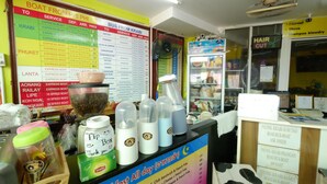 A travel agency with a boat and bus service board, a coffee bar, and a hair salon. - RC Guesthouse (Ko Phi Phi)
