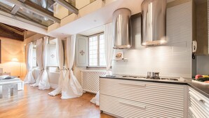 Una cocina moderna con una isla central, electrodomésticos de acero inoxidable y un ventanal con cortinas.