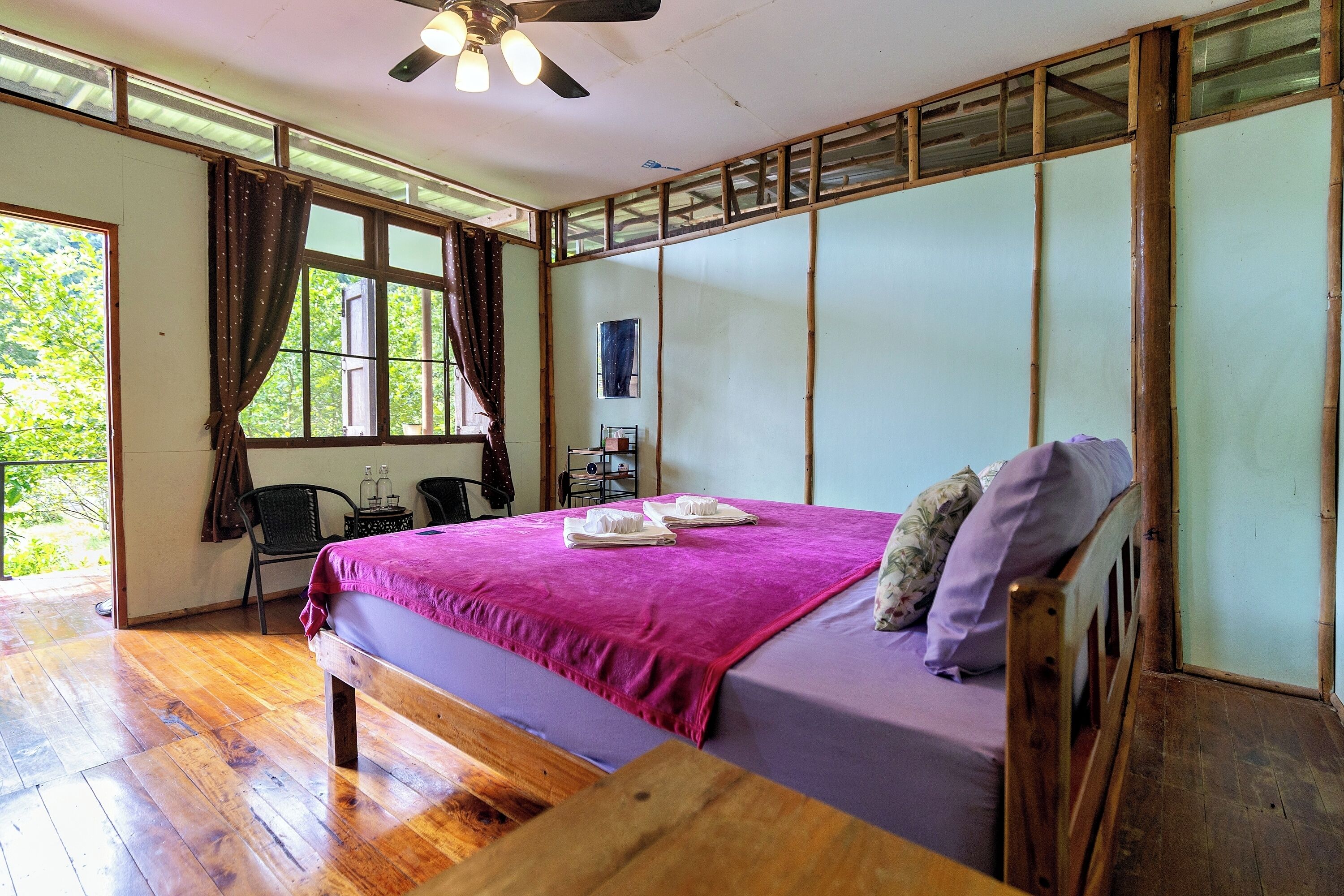 Una habitación con cama, muebles de madera, ventilador de techo y ventana con cortinas.