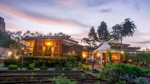 A rustic wooden building with a covered outdoor area, surrounded by lush greenery and terraced gardens. - Bansuanphutarn (Ban Ta Khun)