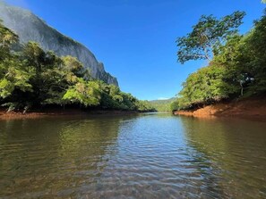 Une rivière bordée d’une végétation luxuriante et d’une falaise imposante.