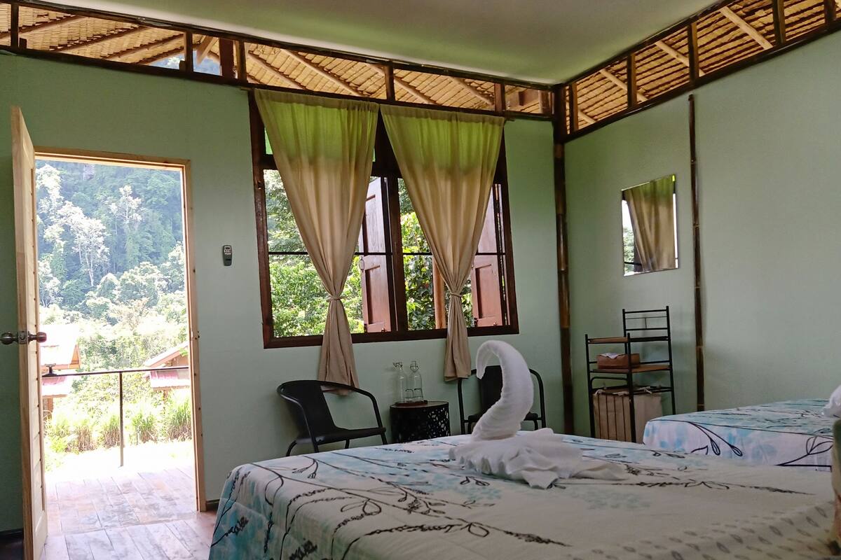 Una habitación con dos camas, una silla, una mesita, un espejo y una ventana con cortinas.