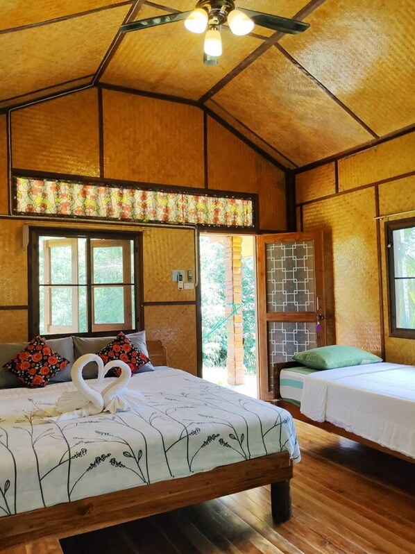 A wooden room with a bed, two windows, a ceiling fan, and a view of greenery outside. - Bansuanphutarn (Ban Ta Khun)