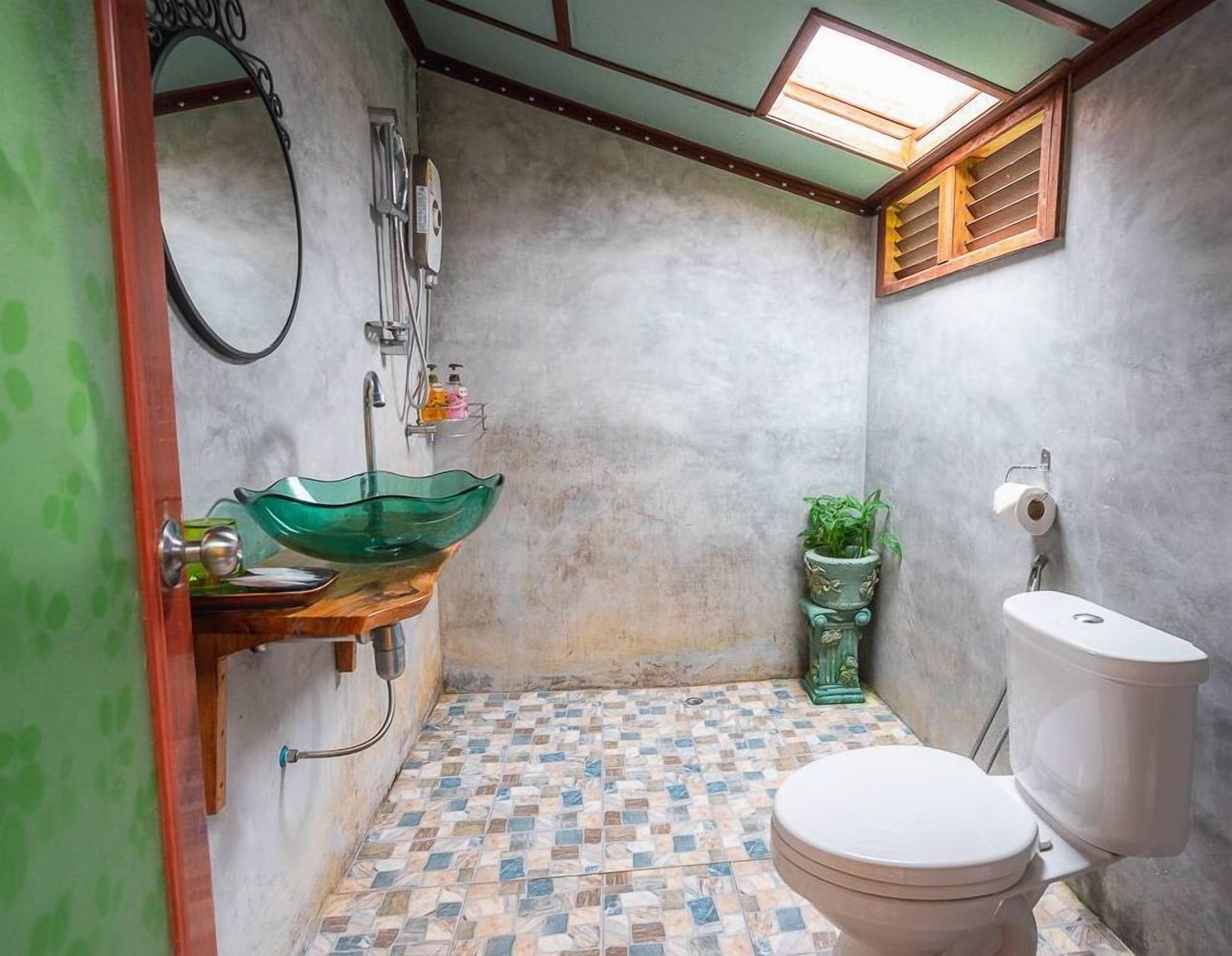 A bathroom with a green glass sink, a white toilet, and a checkered floor.
