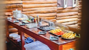 A buffet table with various food items and condiments, set against a wooden cabin backdrop. - Bansuanphutarn (Ban Ta Khun)