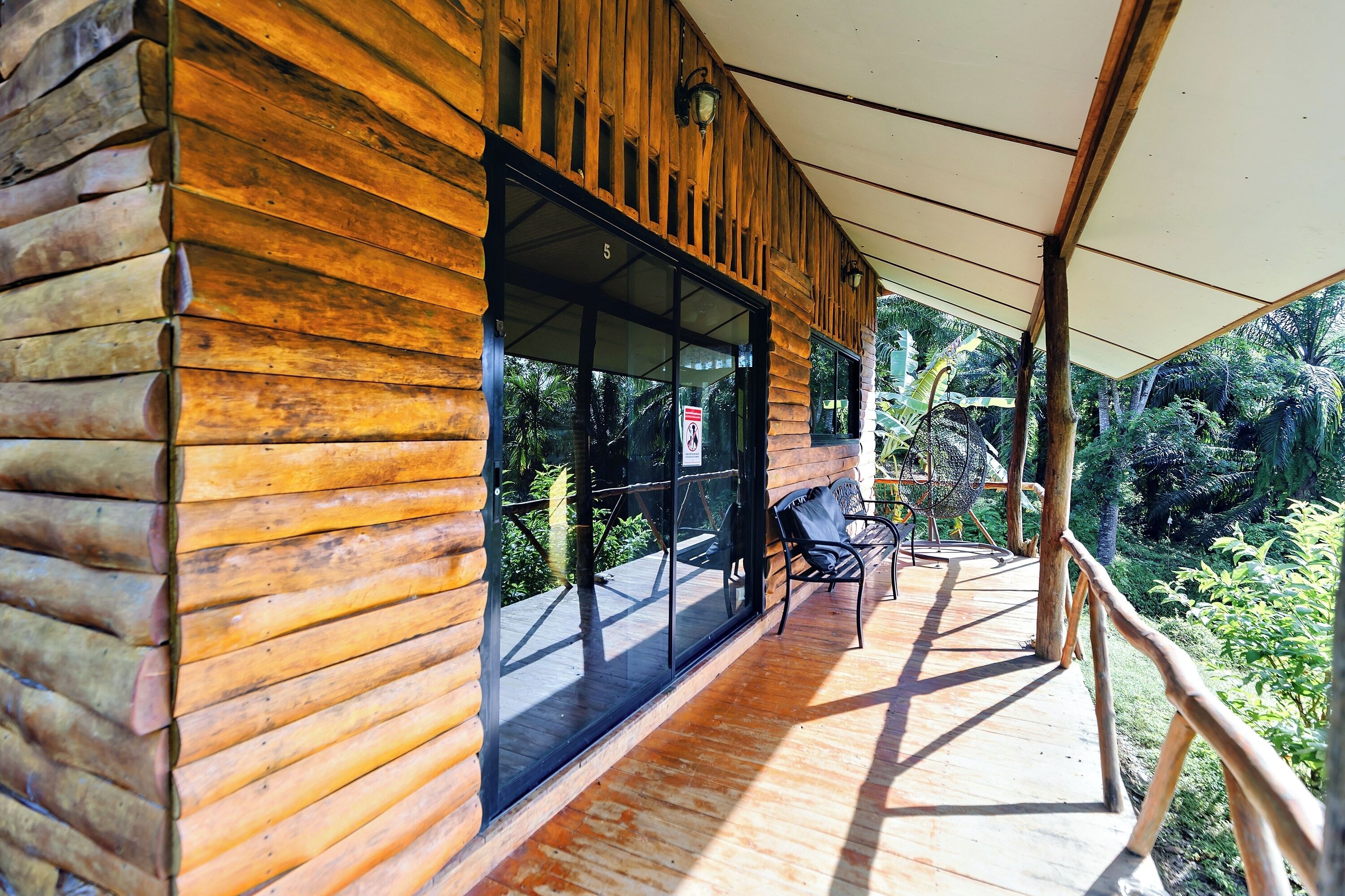 A wooden cabin with a large window and a covered porch.