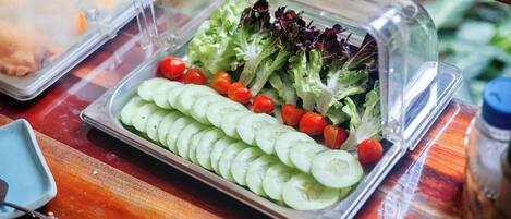 Una mesa de buffet con una bandeja de ensalada, un plato azul y una cuchara.