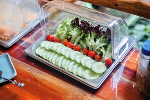 Une table de buffet avec un plateau de salade, une assiette bleue et une cuillère.