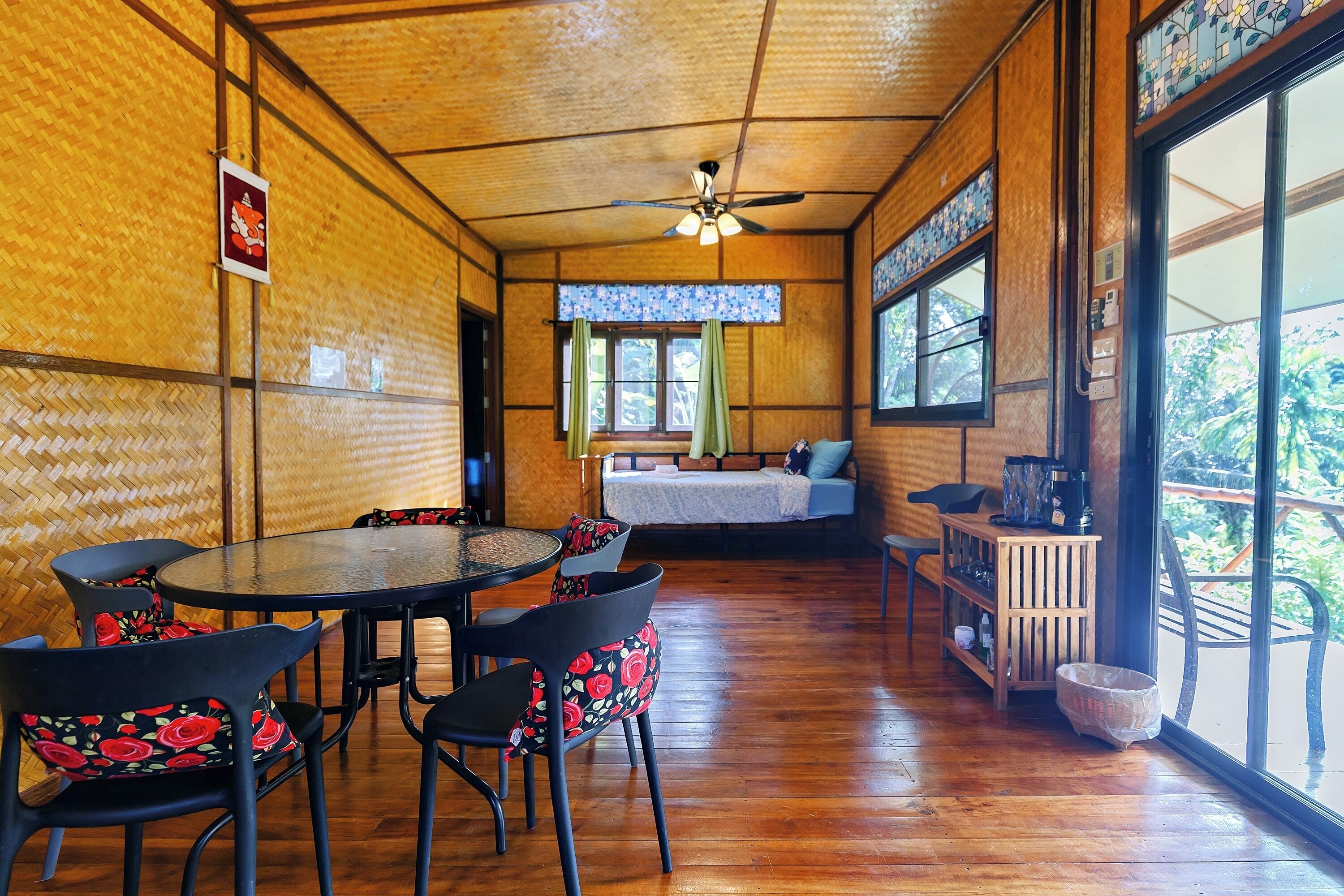 A wooden interior with a dining area, a sofa, and a window with a view.