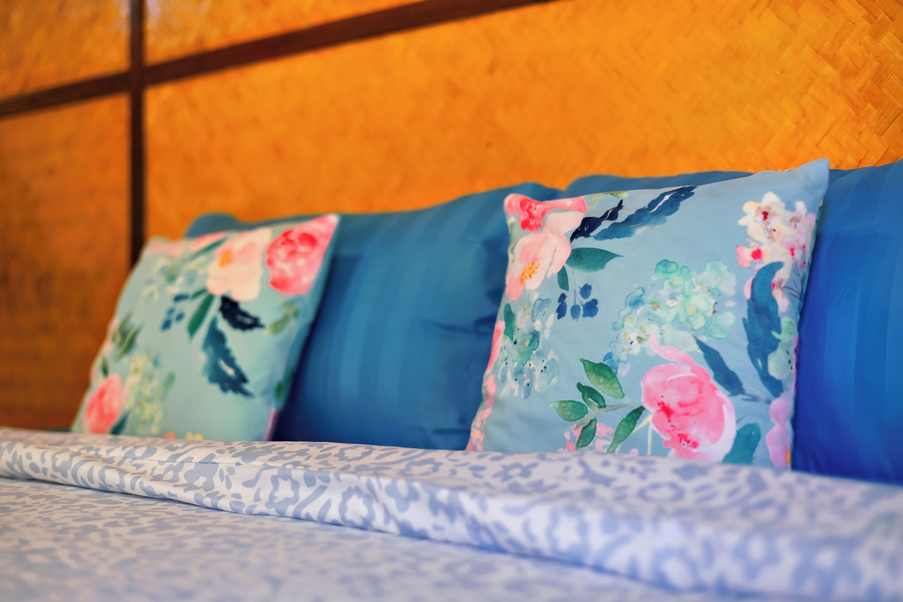 A bed with floral-patterned pillows and a patterned bedspread.