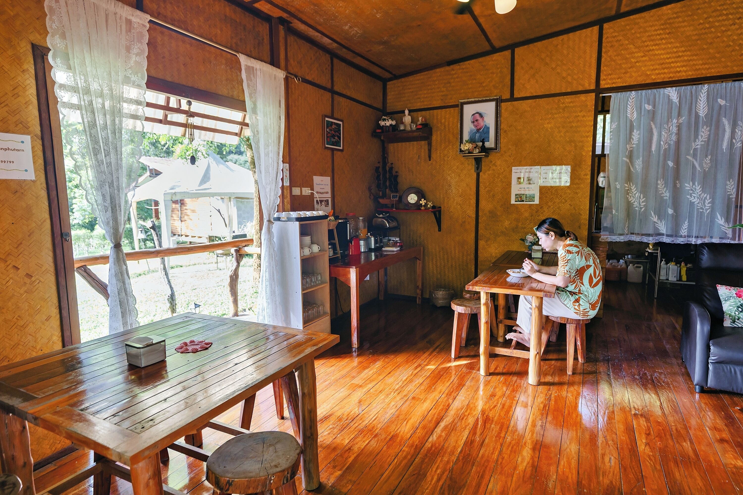 Une pièce avec un plancher en bois, une table et des chaises, un canapé noir et une fenêtre donnant sur l’extérieur.