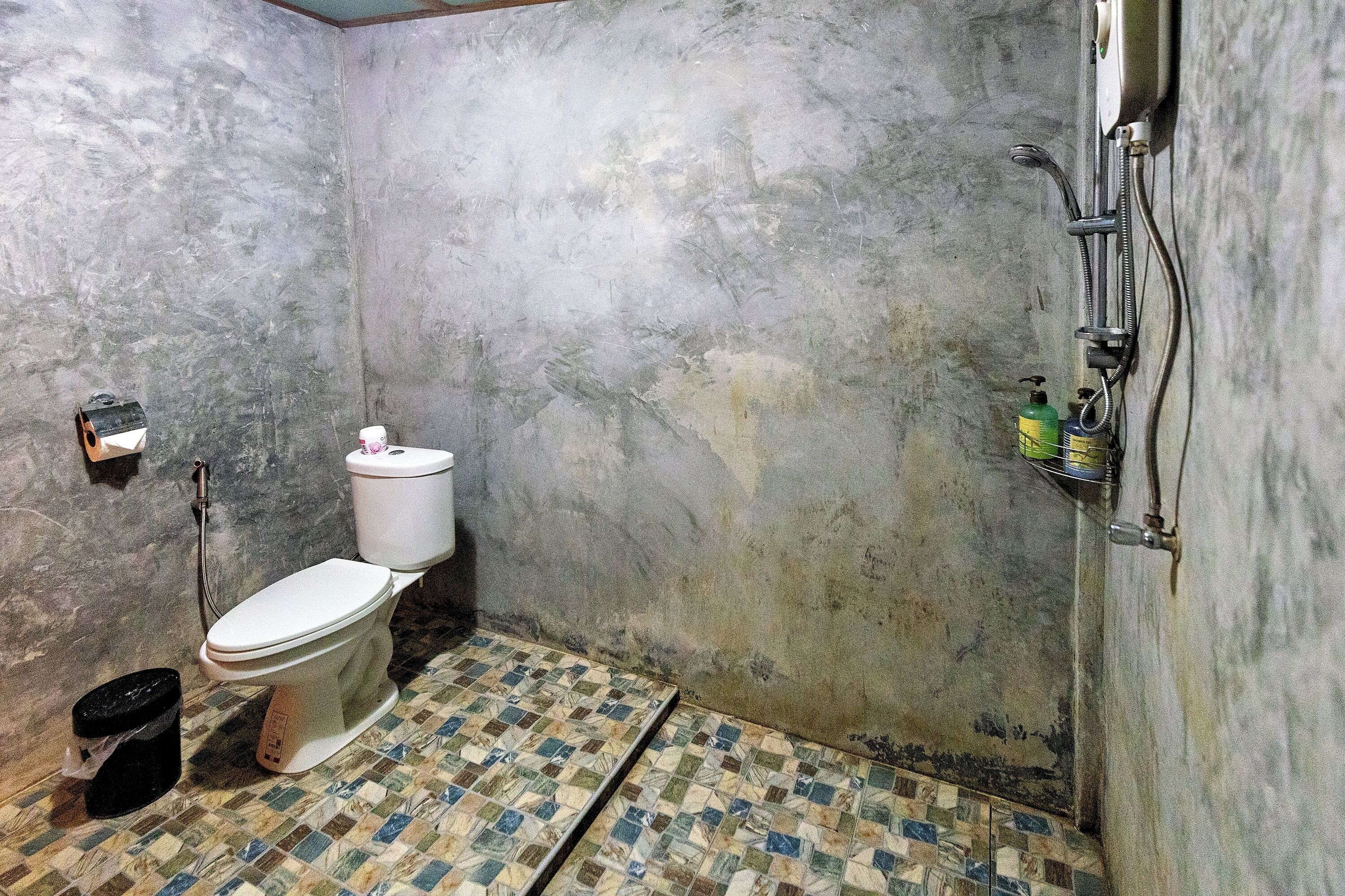 A bathroom with a toilet, a shower, and a tiled floor.