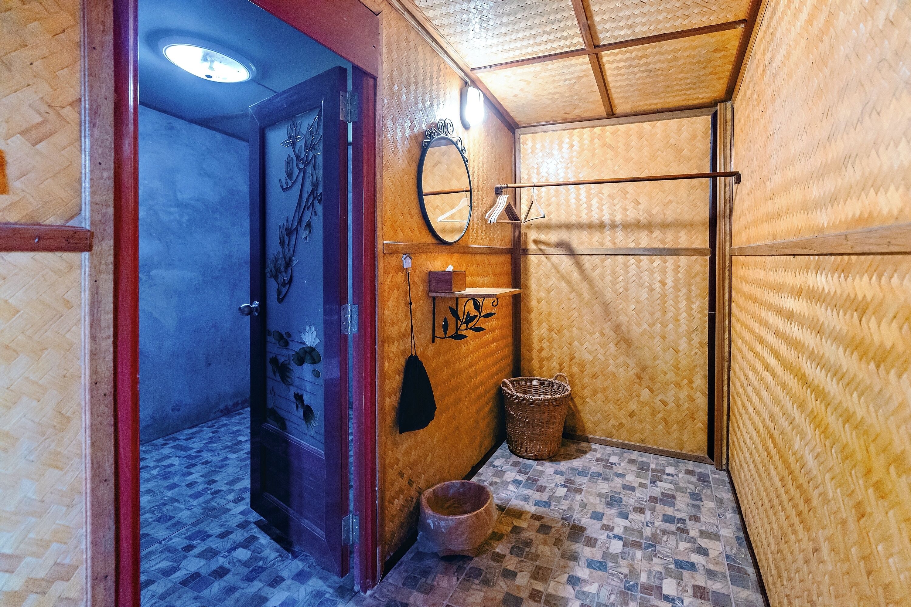 A bathroom with a wooden wall, a mirror, a towel rack, a small basket, and a tiled floor.
