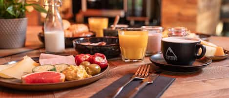 Una mesa de desayuno con platos de comida, una taza de café y una botella de leche.