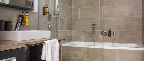 A modern bathroom with a large sink, a bathtub, and a glass-enclosed shower.