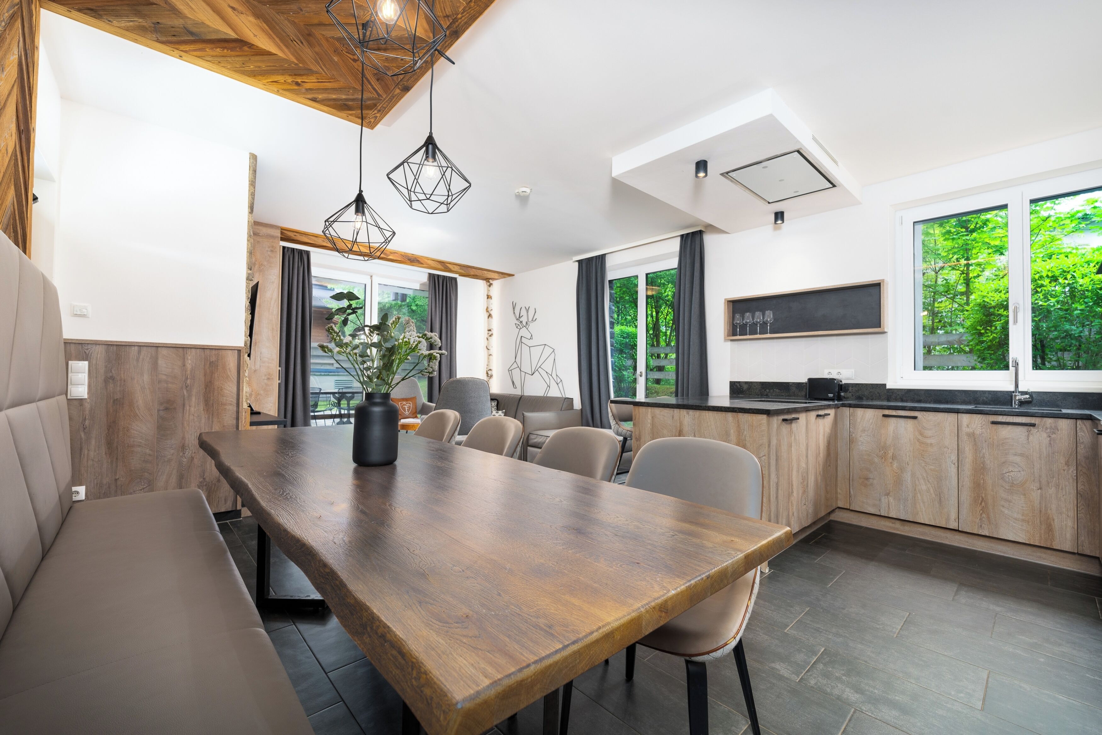 Una cocina moderna con una mesa de comedor de madera, sillas y un amplio ventanal con vistas a zonas verdes.