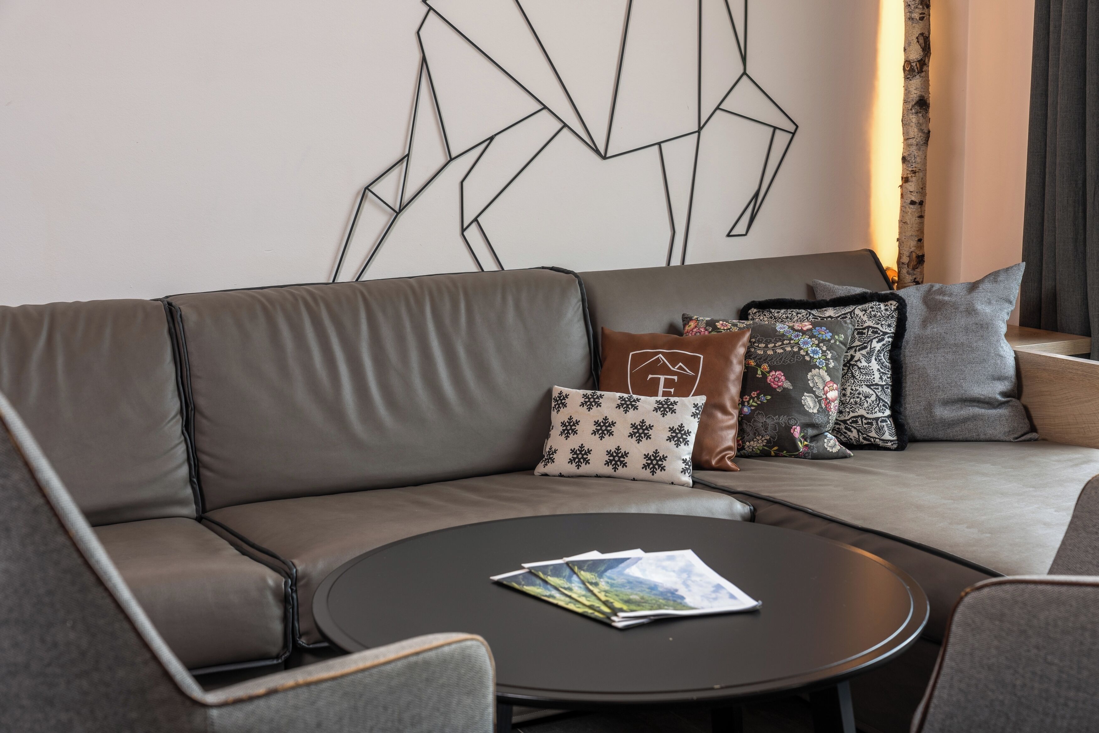 A modern living room with a grey sofa, a round coffee table, and decorative pillows.