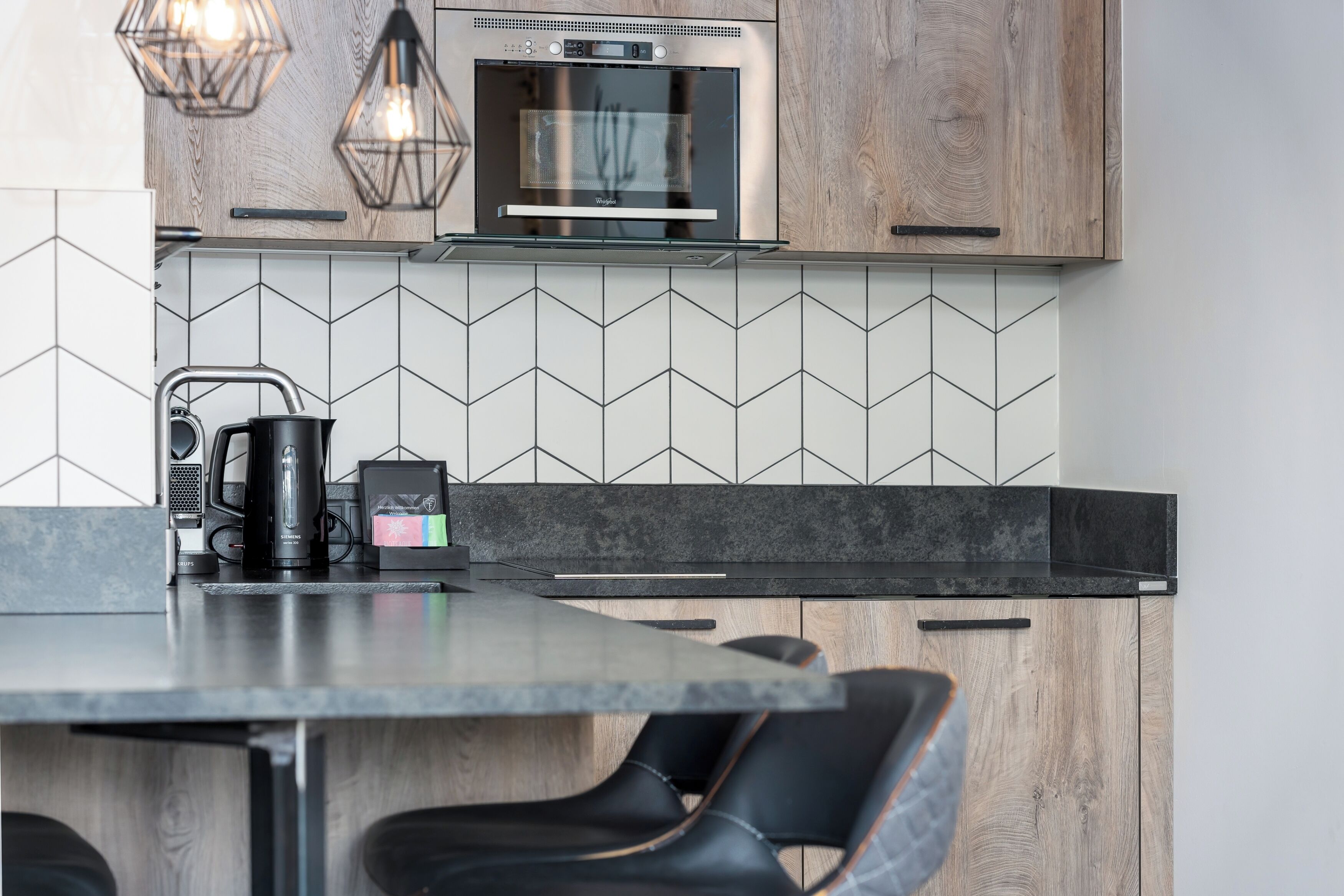 A modern kitchen with a built-in oven, a coffee maker, and a black countertop.
