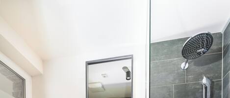 Un baño moderno con tocador de madera, inodoro, espejo grande y zona de ducha.