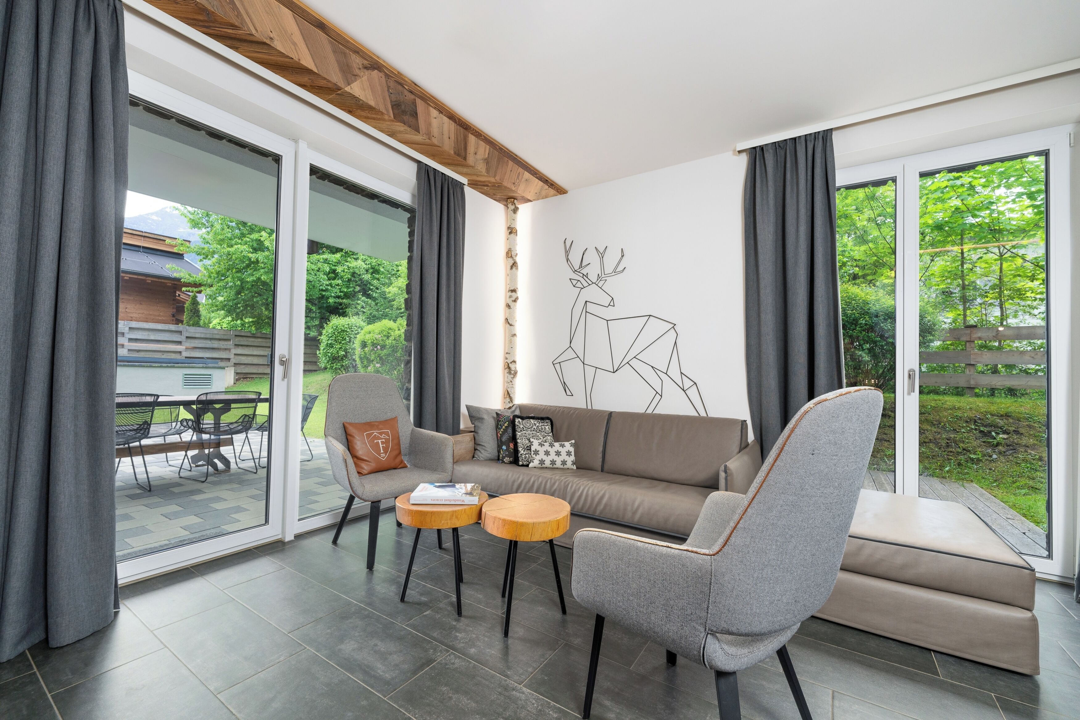 A modern living room with a sofa, two armchairs, a coffee table, and a wall mural of a deer.