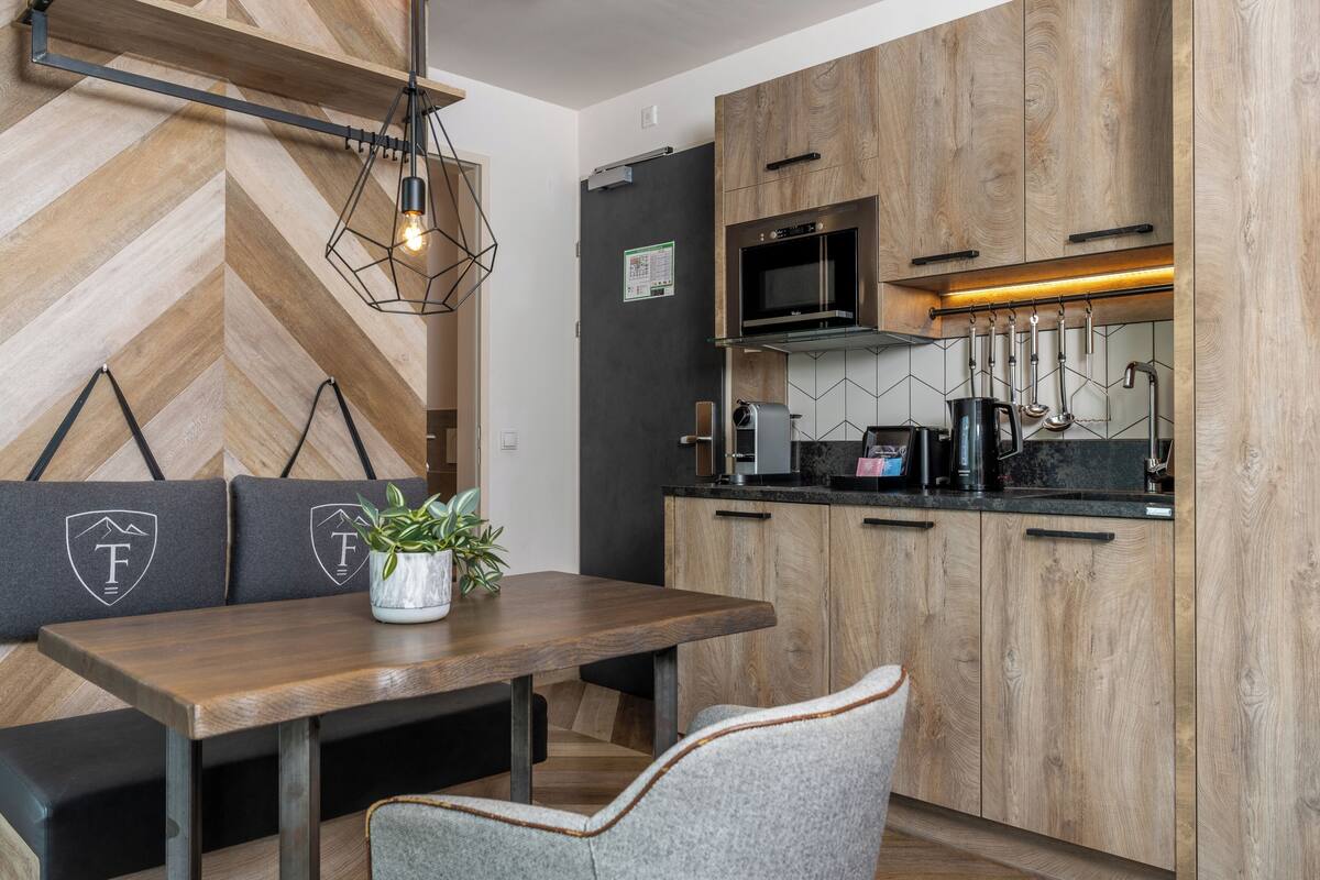 A modern kitchen with wooden cabinets, a built-in microwave, and a coffee machine.