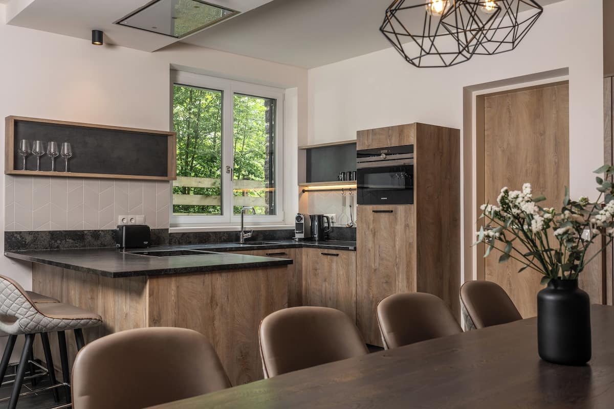 A modern kitchen with wooden cabinets, a built-in oven, and a large window.