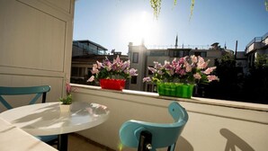 A balcony with a round table and two chairs, potted plants, and a view of buildings in the background. - Paris Garden Hotel Istanbul (Istanbul)
