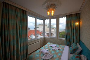A hotel room with a bed, curtains, a chandelier, and a view of buildings through large windows. - Paris Garden Hotel Istanbul (Istanbul)